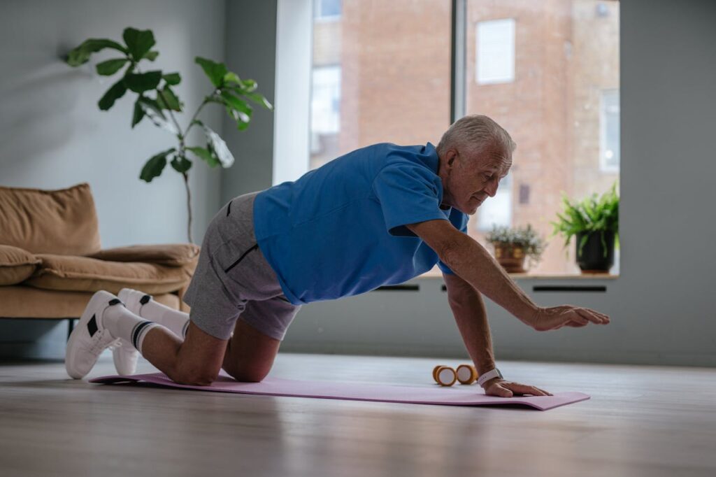Idoso praticando exercício funcional em casa sobre um tapete de yoga, fortalecendo o core, com ambiente iluminado e plantas ao fundo.