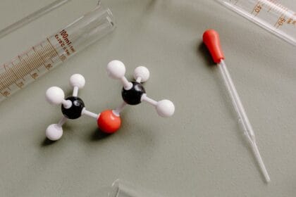 Modelo molecular científico com equipamentos de laboratório representando a composição química das toxinas no organismo e processos de desintoxicação. A estrutura molecular ao lado de proveta graduada e pipeta ilustra como substâncias químicas e compostos tóxicos se acumulam no corpo. Esta representação científica demonstra a importância de desintoxicar o organismo através de chás detox que auxiliam na eliminação de metais pesados, radicais livres e outras toxinas em nível celular. A química da desintoxicação natural envolve compostos bioativos presentes em chás e ervas que promovem a limpeza profunda do fígado e rins.